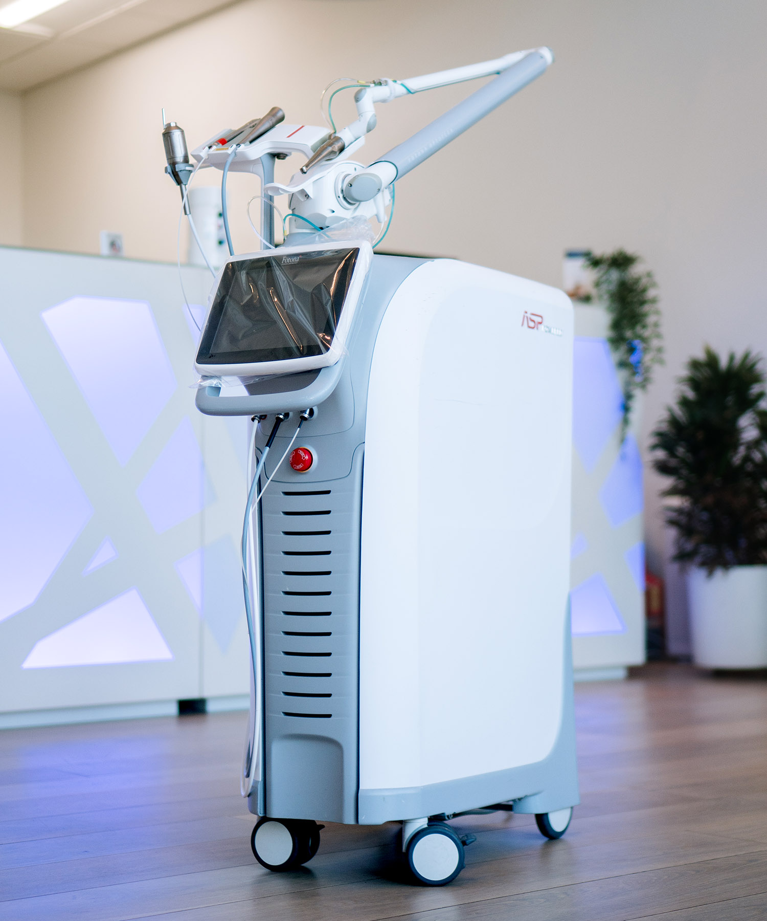 A sleek, upright white and gray Fotona dental laser system standing on wheels in a modern clinic.