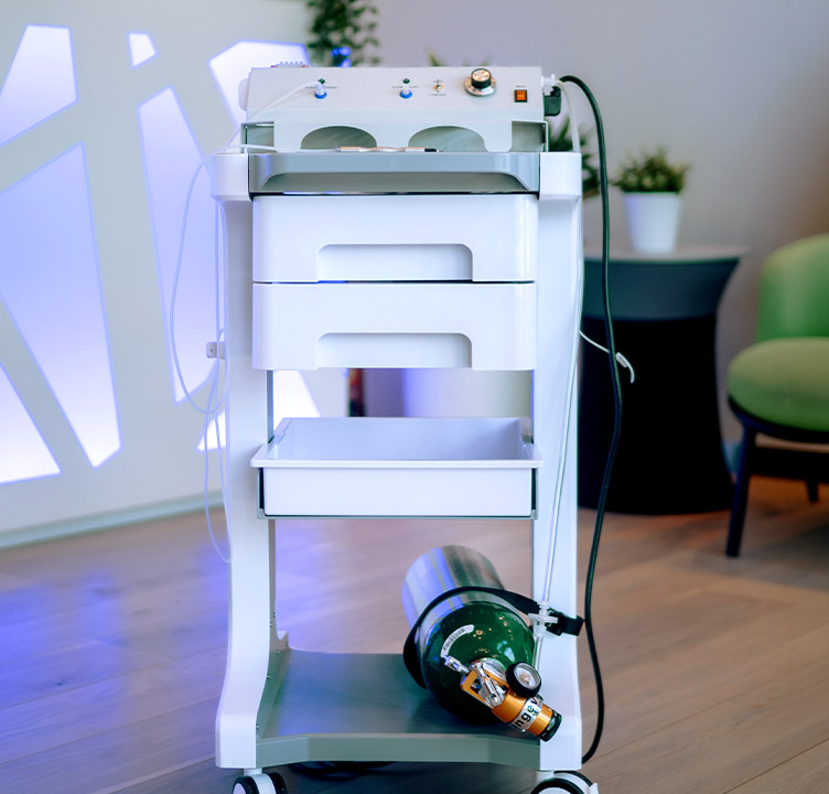 An oxygen-ozone dental therapy cart equipped with a medical gas cylinder, used during safe root canal removal to support healing and reduce microbial burden.